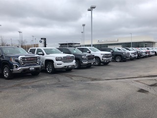 A row of trucks at a dealership for fleet washing.