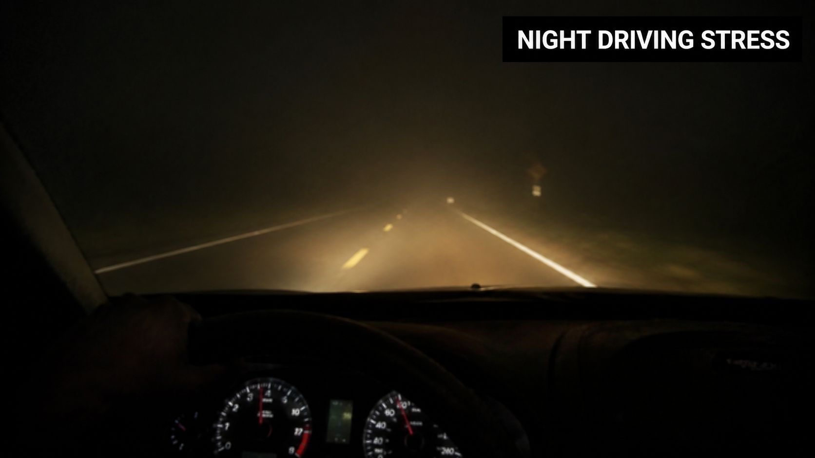 A view from inside a car driving at night on a foggy road with poor visibility.