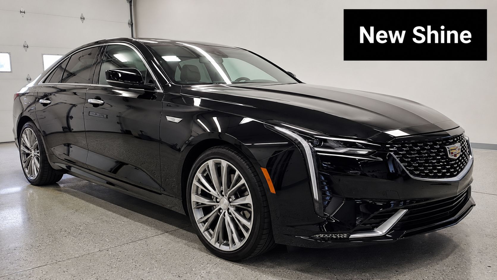 A sleek, black Cadillac luxury sedan in a bright, clean garage after a professional paint protection treatment.
